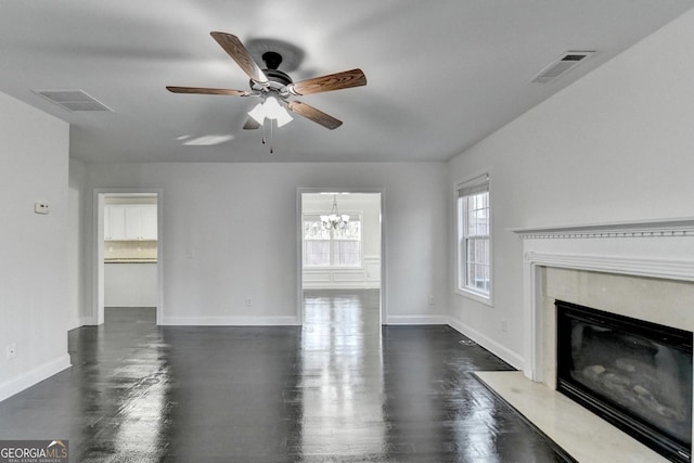 unfurnished living room featuring a fireplace and ceiling fan with notable chandelier