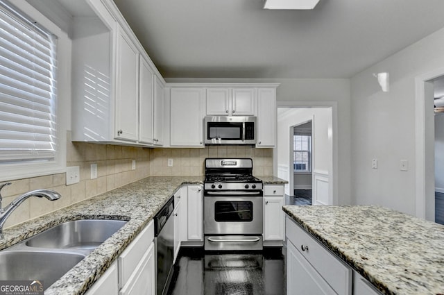 kitchen featuring white cabinets, appliances with stainless steel finishes, light stone countertops, and sink