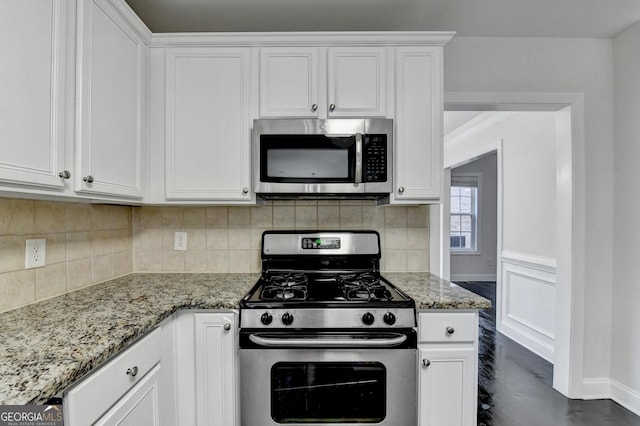 kitchen with white cabinetry, light stone counters, and appliances with stainless steel finishes