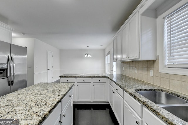 kitchen featuring white cabinetry, light stone countertops, hanging light fixtures, tasteful backsplash, and stainless steel fridge with ice dispenser