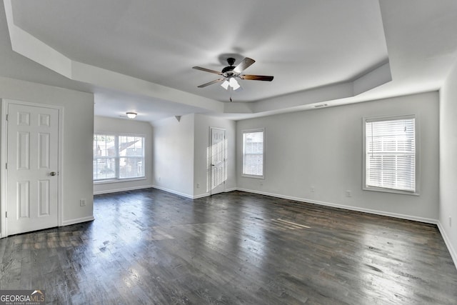 spare room with a tray ceiling, ceiling fan, and dark hardwood / wood-style floors