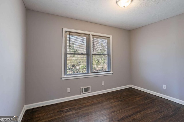 empty room featuring a textured ceiling and dark hardwood / wood-style flooring