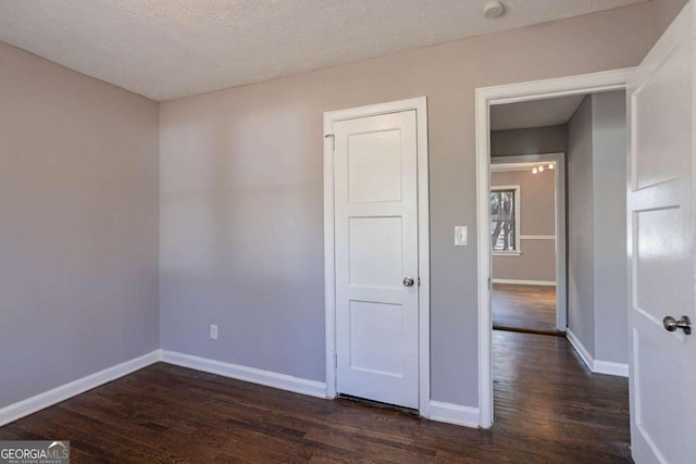 empty room with a textured ceiling and dark hardwood / wood-style floors