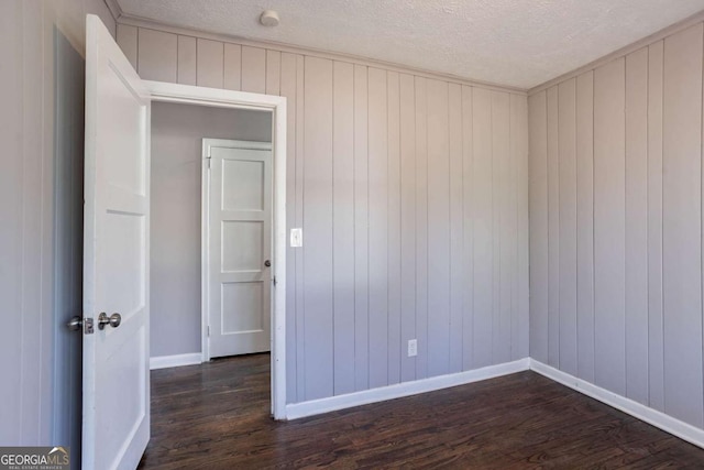 spare room with a textured ceiling and dark wood-type flooring