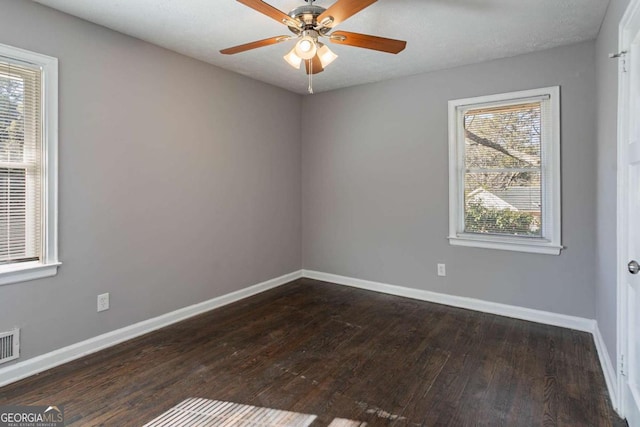 spare room with a textured ceiling, a wealth of natural light, dark wood-type flooring, and ceiling fan