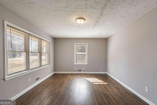 unfurnished room with a textured ceiling and dark wood-type flooring