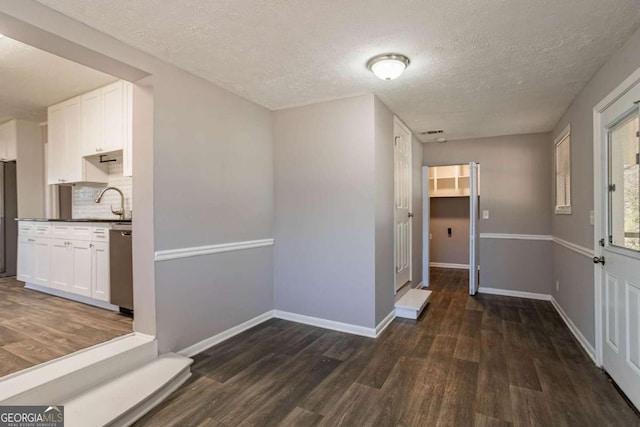 hall with a textured ceiling and dark wood-type flooring