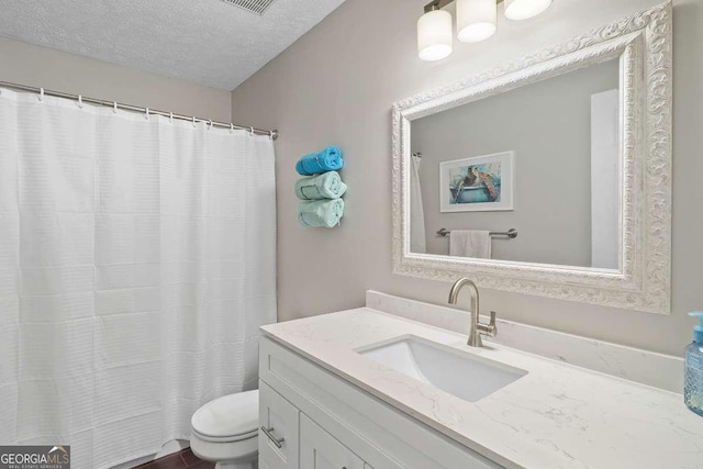 bathroom with vanity, a textured ceiling, and toilet