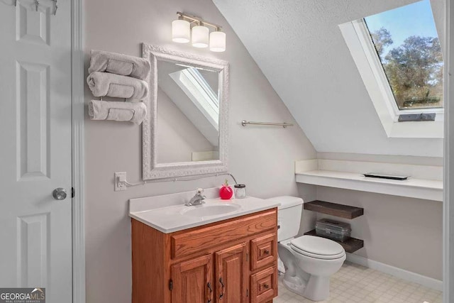 bathroom with a textured ceiling, vanity, toilet, and vaulted ceiling with skylight