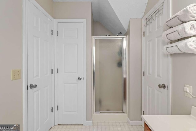 bathroom featuring a shower with door, vanity, and vaulted ceiling