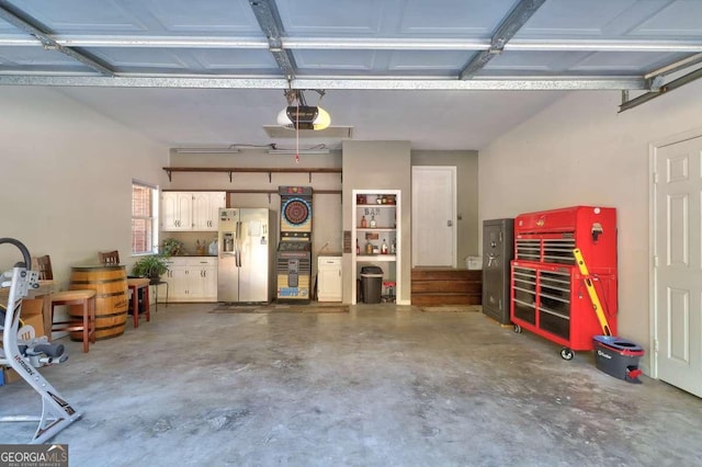 garage featuring stainless steel refrigerator with ice dispenser and a garage door opener