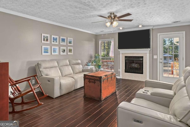 living room with a textured ceiling, ceiling fan, crown molding, a fireplace, and dark hardwood / wood-style floors