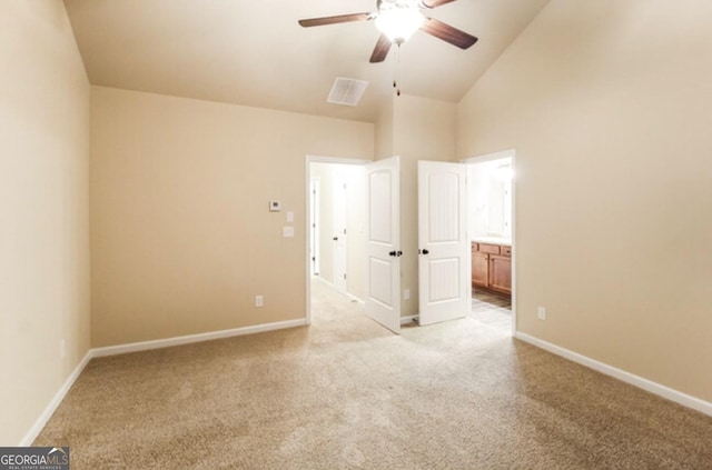 unfurnished bedroom featuring light carpet, high vaulted ceiling, ensuite bath, and ceiling fan