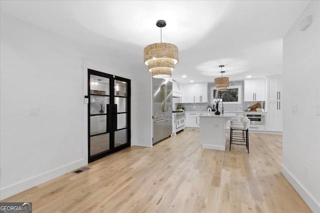 kitchen with hanging light fixtures, white cabinetry, decorative backsplash, and a kitchen island