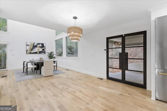 unfurnished dining area with a healthy amount of sunlight, light wood-type flooring, and a notable chandelier