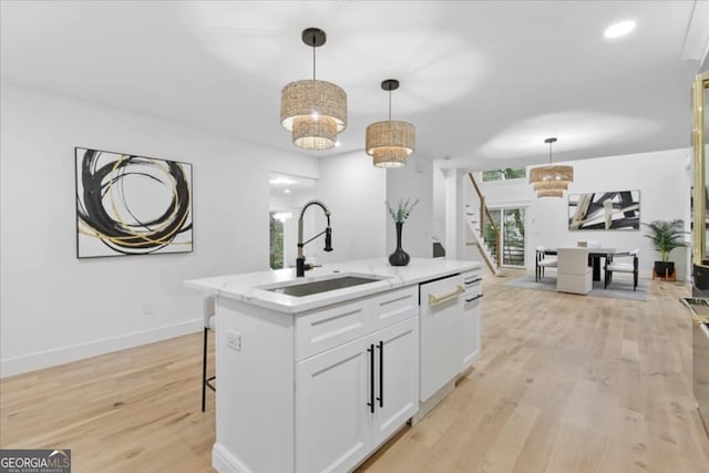 kitchen featuring dishwasher, hanging light fixtures, a kitchen island with sink, white cabinets, and sink