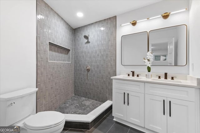 bathroom featuring tiled shower, tile patterned flooring, vanity, and toilet