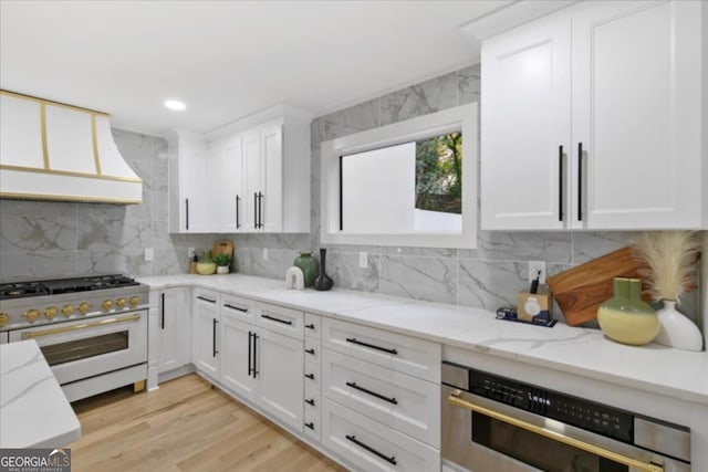 kitchen featuring stainless steel appliances, light stone countertops, white cabinets, and tasteful backsplash