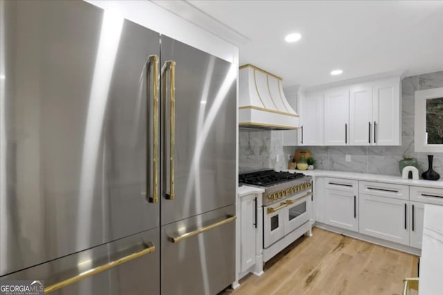 kitchen featuring tasteful backsplash, white cabinets, high end appliances, and custom range hood