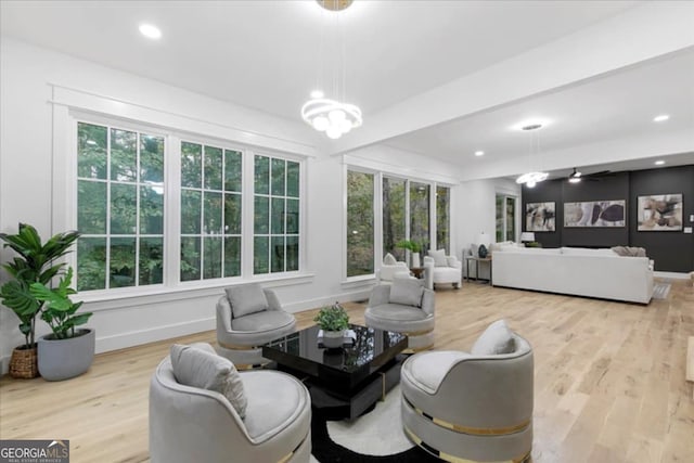 living room featuring light wood-type flooring, a wealth of natural light, and ceiling fan with notable chandelier