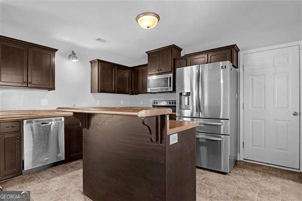 kitchen featuring a kitchen breakfast bar, a kitchen island, dark brown cabinets, and stainless steel appliances