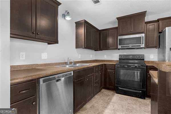 kitchen featuring dark brown cabinetry, stainless steel appliances, and sink