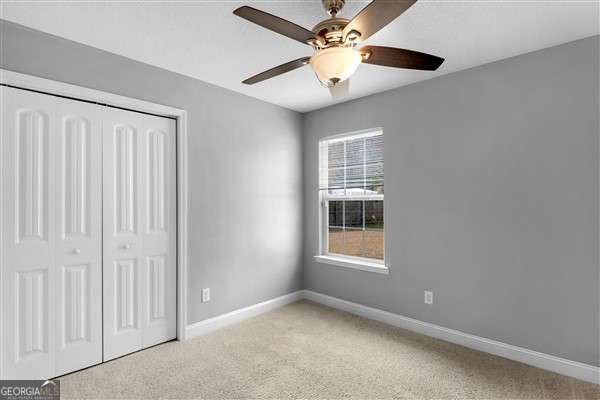 unfurnished bedroom with ceiling fan, a closet, and light carpet