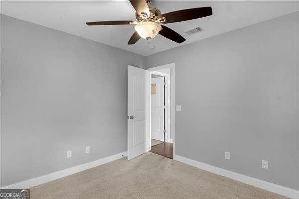 unfurnished room featuring light carpet and ceiling fan