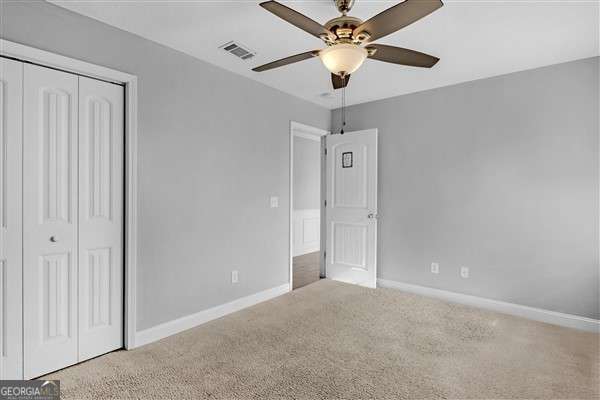 unfurnished bedroom featuring ceiling fan, a closet, and light carpet