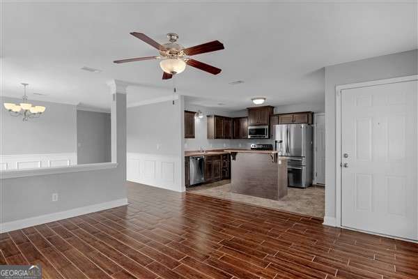 unfurnished living room featuring ceiling fan with notable chandelier