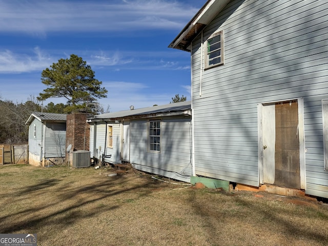 back of property with central AC unit and a yard