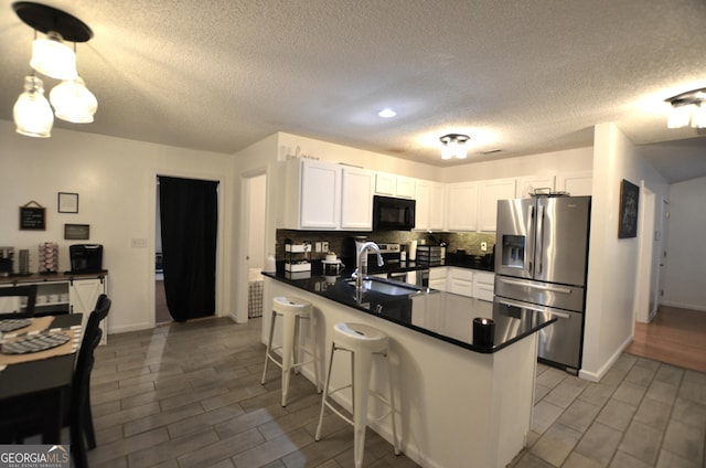 kitchen with a breakfast bar, kitchen peninsula, appliances with stainless steel finishes, tasteful backsplash, and white cabinetry