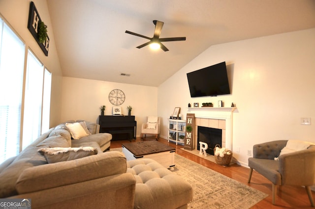 living room featuring a fireplace, wood-type flooring, vaulted ceiling, and ceiling fan