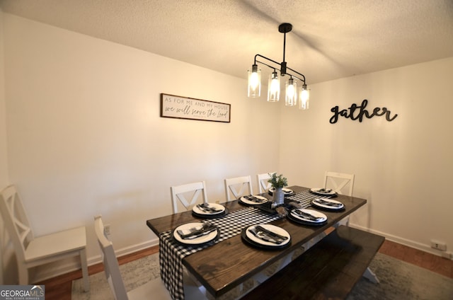 dining space with hardwood / wood-style flooring, a textured ceiling, and a chandelier