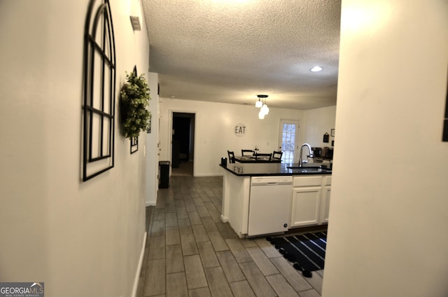 kitchen with dishwasher, white cabinets, a textured ceiling, and sink