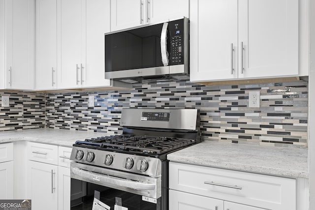 kitchen featuring backsplash, light stone counters, white cabinets, and appliances with stainless steel finishes