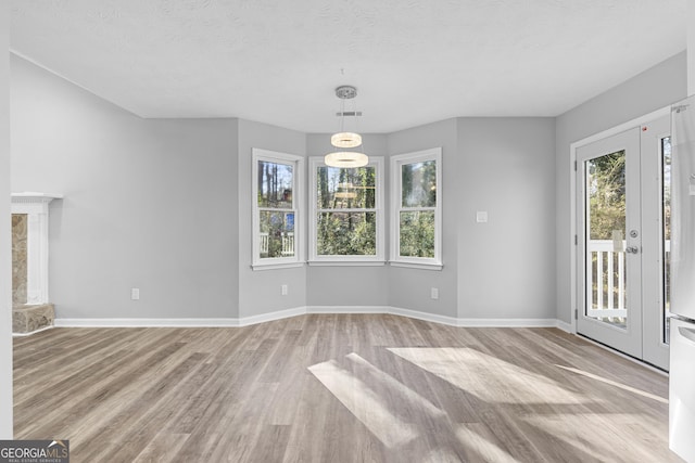 interior space featuring light hardwood / wood-style floors, a textured ceiling, and an inviting chandelier