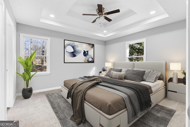 carpeted bedroom featuring a raised ceiling and ceiling fan