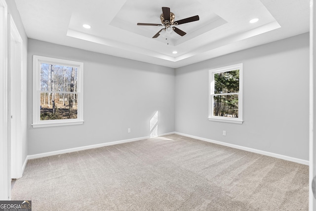 empty room with carpet, a tray ceiling, plenty of natural light, and ceiling fan