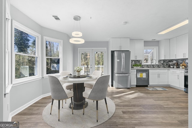 dining space with hardwood / wood-style floors, plenty of natural light, sink, and french doors