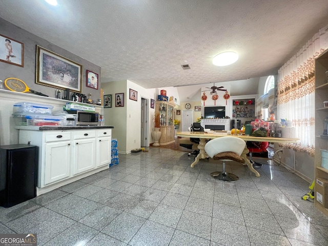 kitchen with ceiling fan, white cabinets, and a textured ceiling