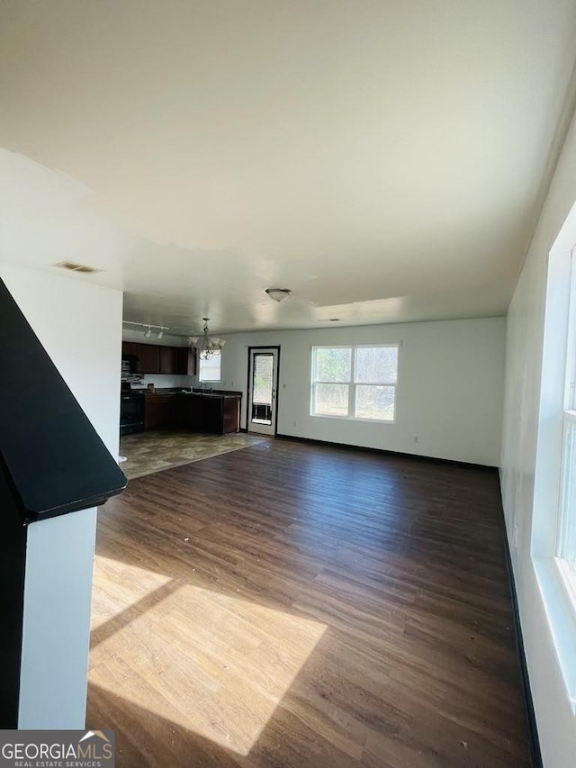 unfurnished living room with dark wood-type flooring and an inviting chandelier