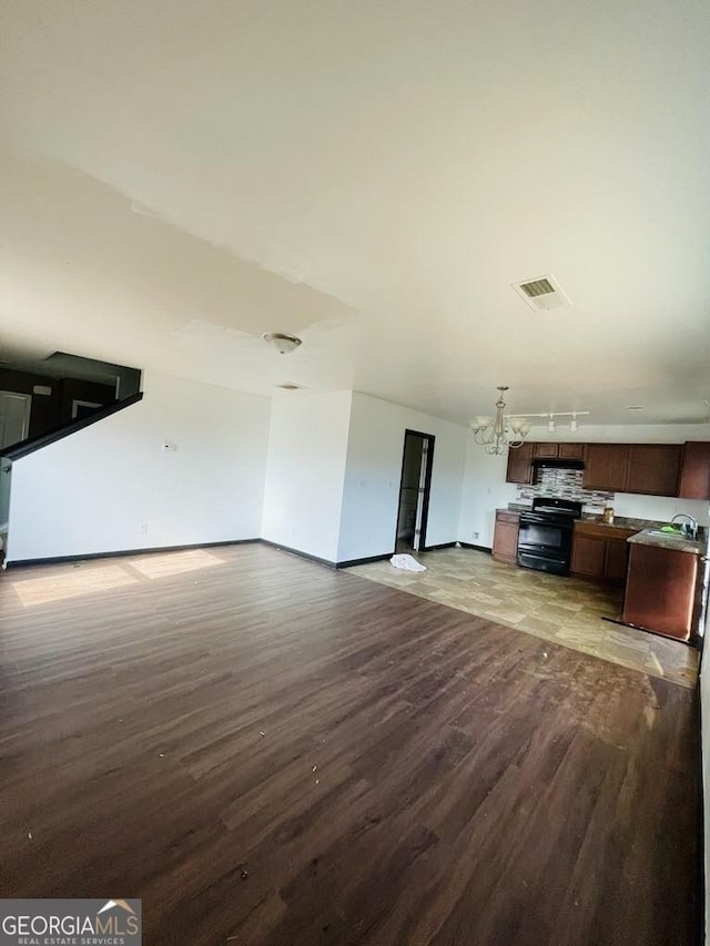 unfurnished living room featuring wood-type flooring, a notable chandelier, and sink