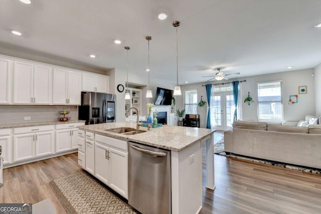 kitchen with white cabinetry, sink, stainless steel appliances, and a center island with sink