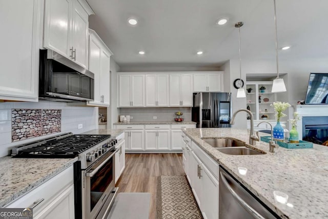 kitchen with white cabinets, appliances with stainless steel finishes, pendant lighting, and sink