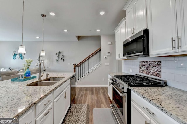 kitchen featuring sink, hardwood / wood-style floors, pendant lighting, white cabinets, and appliances with stainless steel finishes