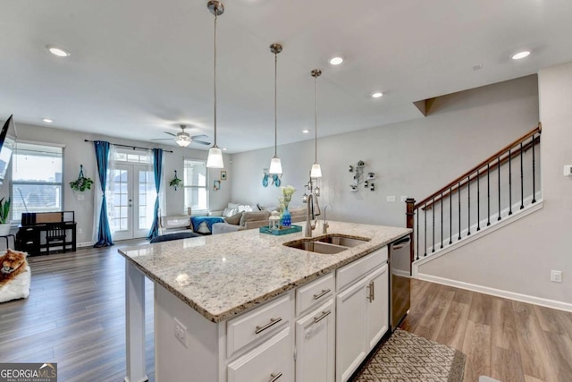 kitchen with white cabinets, sink, stainless steel dishwasher, ceiling fan, and an island with sink