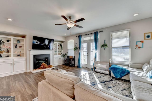 living room with french doors, hardwood / wood-style flooring, built in features, and ceiling fan