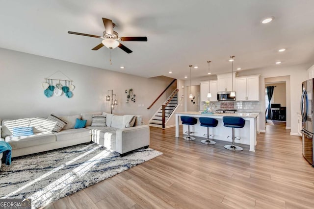 living room featuring light hardwood / wood-style floors, ceiling fan, and sink