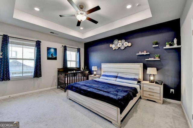 carpeted bedroom featuring a tray ceiling and ceiling fan